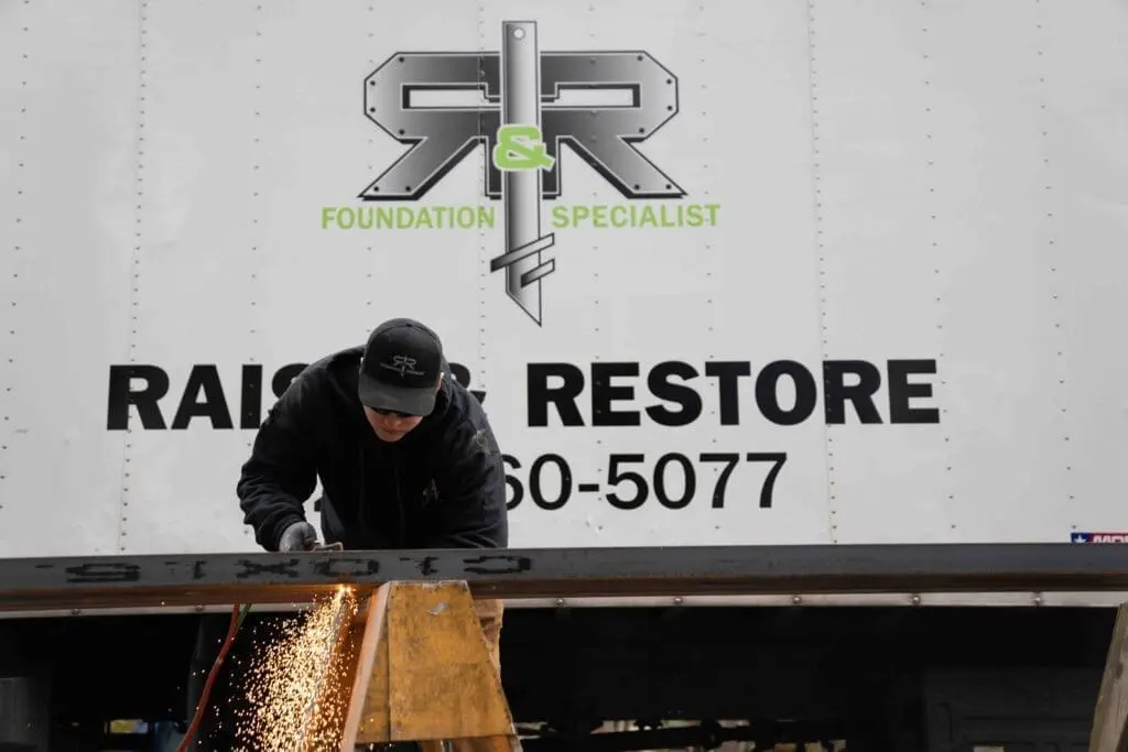 Mike torching hold in C-Chanel while working on site for residential foundation repair services