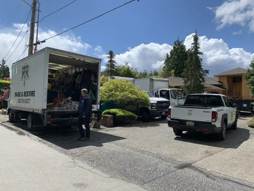 four R&R trucks in a driveway outside a house and onsite for a customer. Box truck is open and the equipment inside is visible